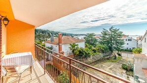 Un balcón con una silla y una mesa de metal, con vistas a una zona residencial con casas y vegetación.