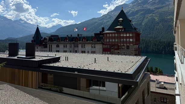 Un hôtel doté d’une terrasse sur le toit, offrant une vue sur la montagne et un lac.