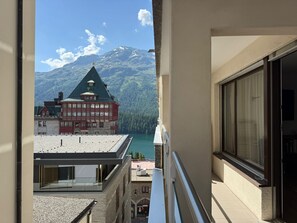 Un balcone con vista sulle montagne, un edificio con facciata rossa e cielo sereno.