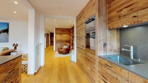 A modern kitchen with wooden cabinetry, a built-in oven, and a stainless steel sink. - Apartmenthouse house next to the lake in St. (St. Moritz)