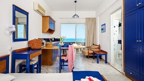 A room with a bed, a desk, a chair, a window with a view of the sea, and a wardrobe. - Matzi Apartments (Platanias)