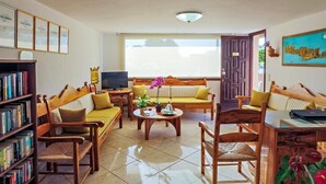 A cozy living room with a sofa, chairs, a coffee table, and a bookshelf. - Matzi Apartments (Platanias)