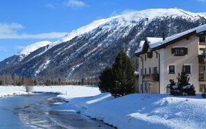 Paisatge nevat amb un edifici que té balcons i un riu.