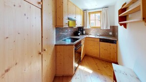 A compact kitchen with wooden cabinets, a built-in oven, and a sink. - The traditional Chesa Marmotta is situated next to the famous River "Inn" in a v (Celerina/Schlarigna)