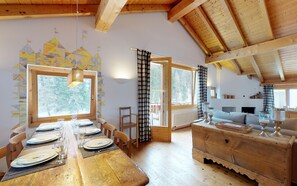 A wooden dining table set for four with a view of trees outside. - Quiet location at the beginning of the forest, next to the cross-country-slopes. (St. Moritz)