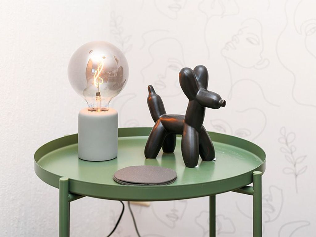 Une table sur laquelle se trouvent une ampoule, une petite sculpture et un objet circulaire.