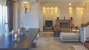 Una sala de estar con chimenea, televisión y un comedor con velas.