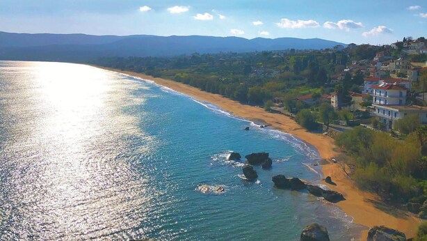Un pueblo costero con playa, costa rocosa y edificios residenciales.