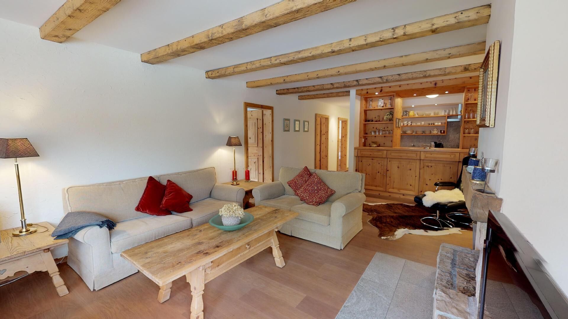Ein gemütliches Wohnzimmer mit einer Couch, einem Couchtisch und einem Essbereich mit Holzbalken.