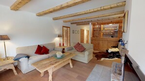 Un salon chaleureux avec un canapé, une table basse et un coin repas agrémenté de poutres en bois.