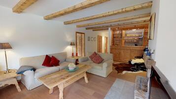 Ein gemütliches Wohnzimmer mit einer Couch, einem Couchtisch und einem Essbereich mit Holzbalken.