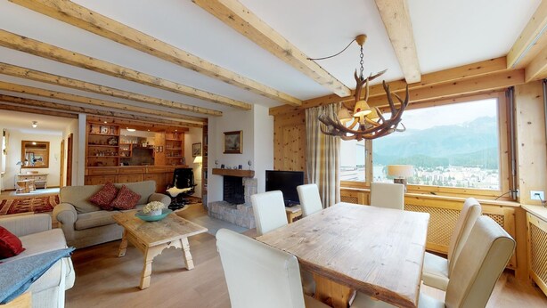 Un salon chaleureux avec une cheminée, des meubles en bois et une grande fenêtre donnant sur une vue imprenable sur les montagnes.