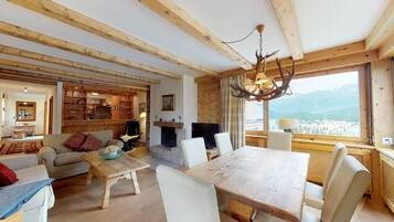 Ein gemütliches Wohnzimmer mit Kamin, Holzmöbeln und einem großen Fenster mit Blick auf die Berge.