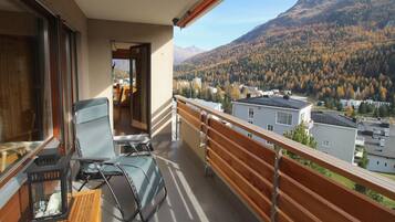 Ein Balkon mit Blick auf eine gebirgige Landschaft, ein Stuhl und ein Tisch mit einer Laterne.