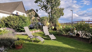 Ein Garten mit zwei Liegestühlen, einem Kiesweg und verschiedenen Pflanzen.