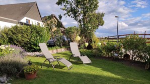 A garden with two lounge chairs, a stone pathway, and a variety of plants. - Apartment with a view, a place to unwind (Brilon)