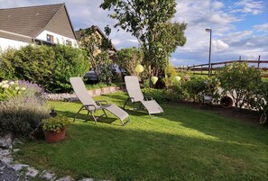 A garden with two lounge chairs, a stone pathway, and a variety of plants. - Apartment with a view, a place to unwind  (Brilon)