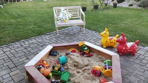 A sandbox with toys, a bench, and a garden in the background. - Apartment with a view, a place to unwind (Brilon)