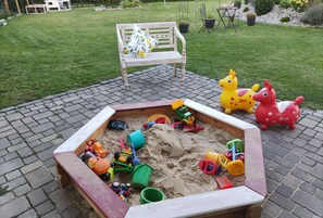 A sandbox with toys, a bench, and a garden in the background. - Apartment with a view, a place to unwind  (Brilon)