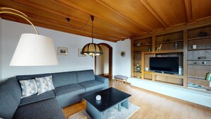 Ein Wohnzimmer mit Sofa, Couchtisch, Fernseher und Holzböden.