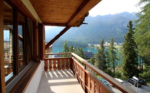 Un balcon doté d’une balustrade en bois, offrant une vue sur un paysage montagneux et un lac.
