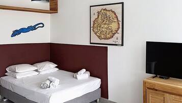 Une chambre d’hôtel équipée d’un lit, d’une télévision, d’un bureau et d’une œuvre d’art accrochée au mur.