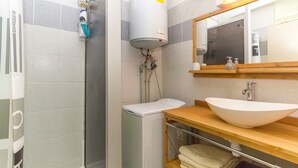 Ein Badezimmer mit Dusche, Toilette, Waschbecken und Spiegel.