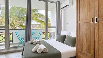 Une chambre à coucher avec un lit, une armoire en bois et un balcon avec des chaises.