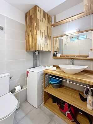 A modern bathroom with a wooden vanity, a white sink, and a compact toilet. - Boucan Beach - Nice studio sea view in Boucan Canot (St Gilles) (Boucan Canot)