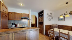 A kitchen with wooden cabinets, a tiled backsplash, and a dining area with a table and chairs. - Very well located apartment house in the area of Park-Salet. (St. Moritz)