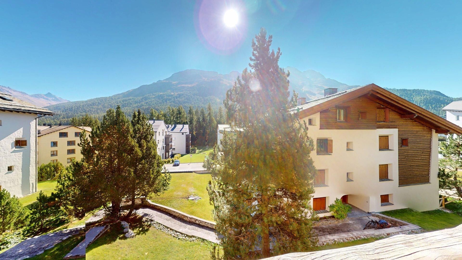 Ein Wohngebiet mit modernen Gebäuden, blauem Himmel und Bergen im Hintergrund.