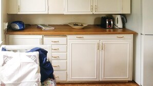 Een keuken met witte kastjes, een houten aanrecht en een waterkoker.