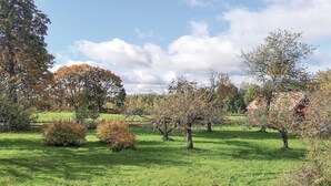 Een landelijk landschap met een grasveld, bomen en een rode schuur.
