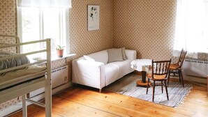 Een gezellige kamer met een stapelbed, een witte bank, een houten tafel en een stoel.
