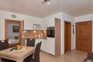 A compact kitchen with white cabinets, a built-in oven, and a coffee maker.