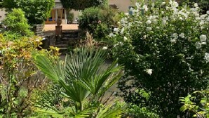 Ein traditionelles Haus mit Ziegelaußenwand, Ziegeldach und einem Garten mit verschiedenen Pflanzen und Blumen.