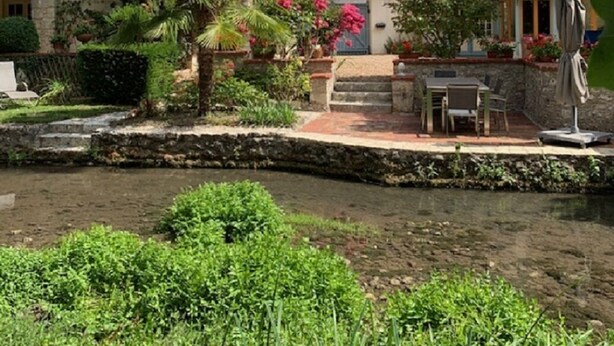 Ein Innenhof mit Teich, Steintreppe, Statue und einer kleinen Sitzgelegenheit im Freien.
