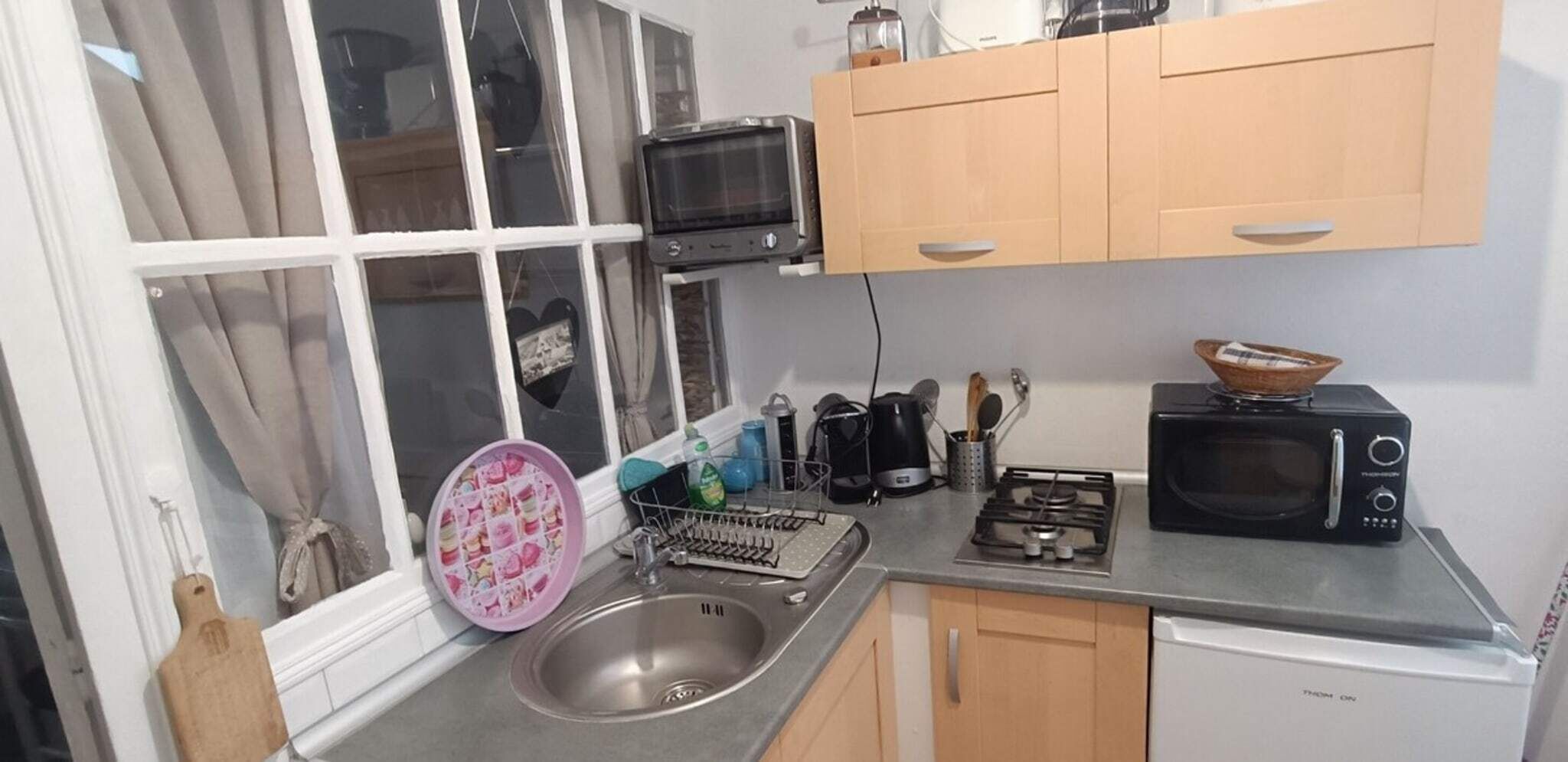 A compact kitchen with a sink, a microwave, a stove, and wooden cabinets.