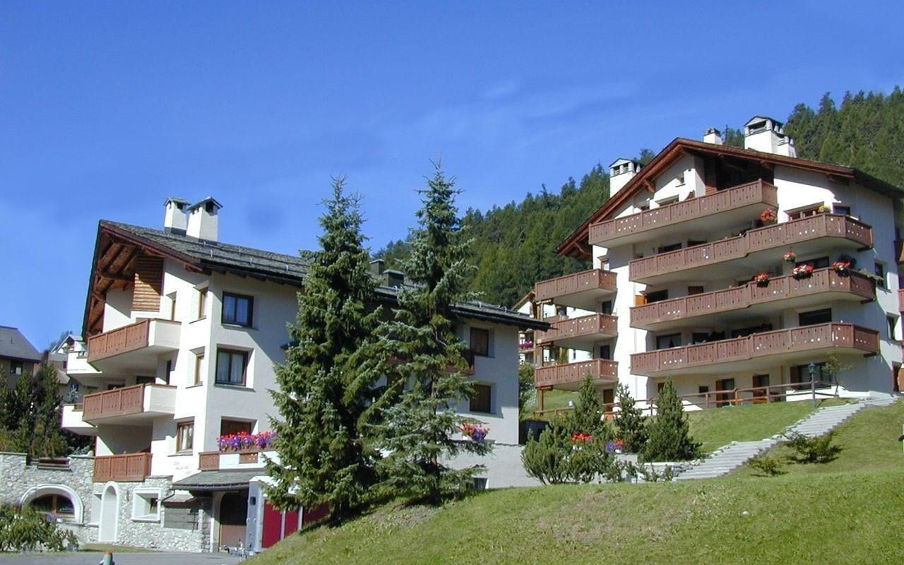 Um hotel com várias andares, varandas, fachada de pedra e localização em encosta.
