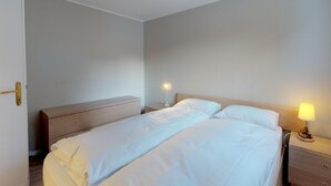 A hotel room with a bed, bedside tables, and a nightstand. - Very well located apartment house in the area of Park-Salet. (St. Moritz)