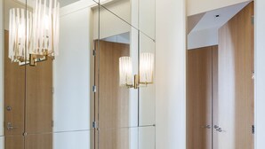 Un hall d’hôtel moderne avec un sol à motifs géométriques, des murs recouverts de miroirs et des portes en bois.
