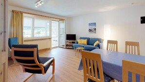 A modern living room with a sofa, chairs, a dining table, and a TV. - Apartment building with excellent infrastructure. (St. Moritz)