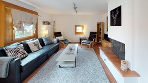 Una sala moderna con un sofá azul oscuro, una mesa de centro blanca y un aparador de madera.