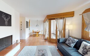 A modern living room with a sofa, a dining area, and a fireplace. - Very well located apartment house in the favorite and quiet Salet area. (St. Moritz)