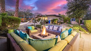 A patio area with outdoor seating, a fire pit, and a house in the background.