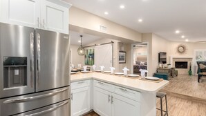 A modern kitchen with stainless steel appliances, a central island, and a dining area with a fireplace.
