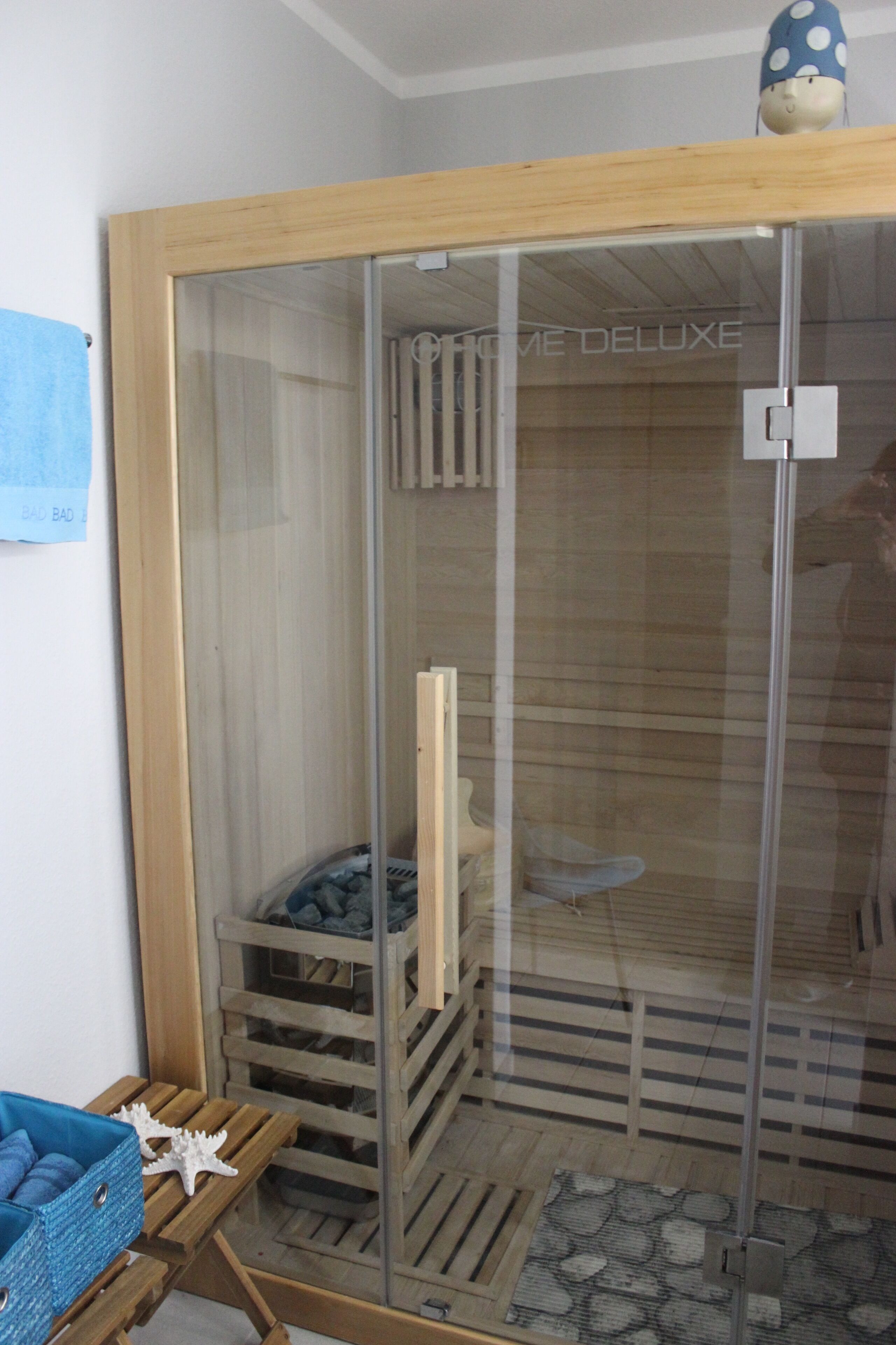 A room with a glass door, wooden furniture, and a blue towel on a rack.