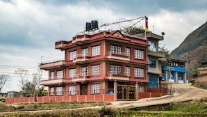 Un immeuble à plusieurs étages, doté d’une façade en briques rouges, de nombreux balcons et d’une entrée fermée par un portail.