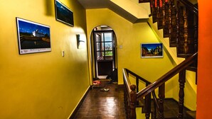 Un couloir doté d’un plancher en bois, de murs jaunes et d’un escalier en bois avec une rampe.
