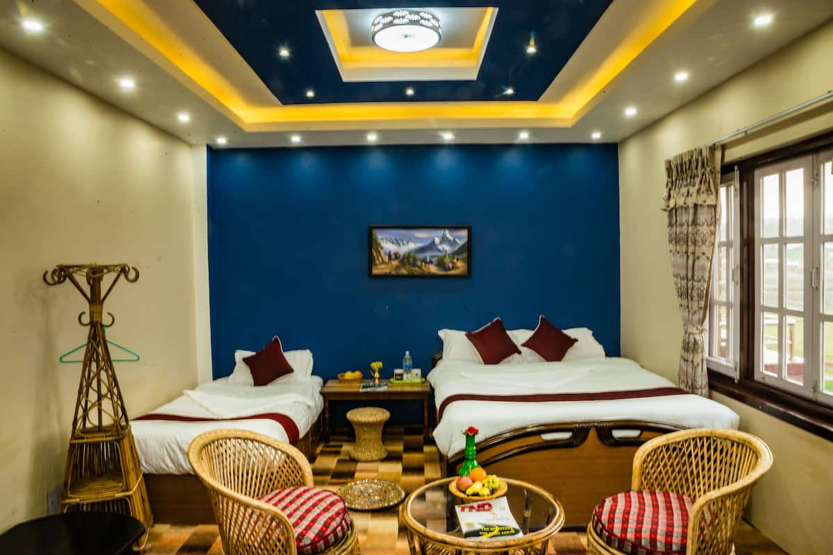 Habitación de hotel con dos camas, una mesita con una cesta de frutas, una silla de mimbre y una silla colgante.